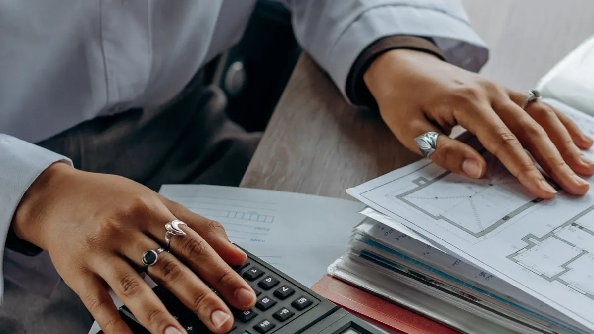 A person using a calculator while reviewing financial paperwork